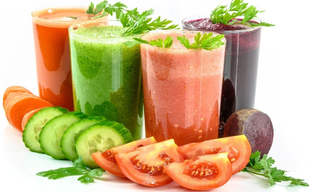 Wielokolorowe smoothie w szklankach z warzyw - pomidory, ogórki, marchew i buraki